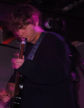 Me playing guitar under purple lighting